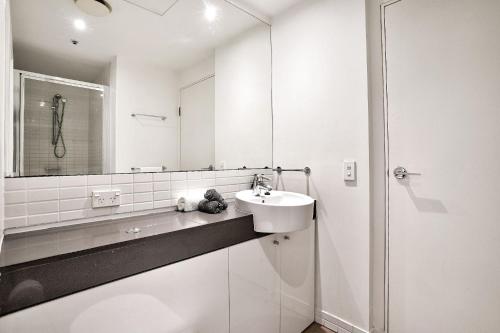 a white bathroom with a sink and a mirror at 903 Harbour Lights with Ocean Views in Cairns