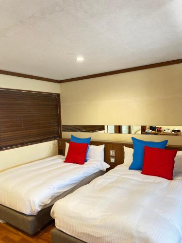 2 Betten in einem Zimmer mit roten und blauen Kissen in der Unterkunft Shonan OVA in Yokosuka