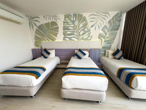 a room with three beds and a couch at Hotel Catedral Plaza in Santa Marta
