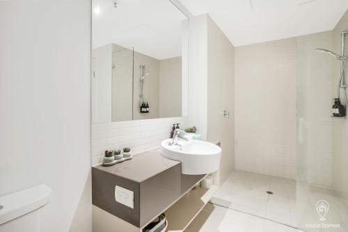 uma casa de banho branca com um lavatório e um espelho em 602 Harbour Lights with Ocean Views em Cairns