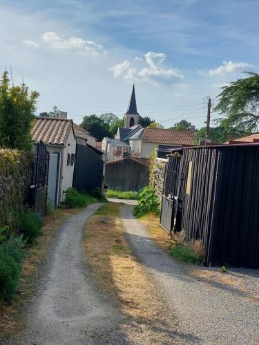 a dirt road with a fence and a church at Virginie & Yann in Saint-Léger-les-Vignes