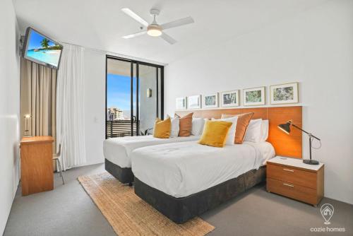 a bedroom with two beds and a ceiling fan at 1101 Harbour Lights with Ocean Views in Cairns