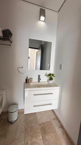a white bathroom with a sink and a mirror at Departamento frente a la bahía in Acapulco