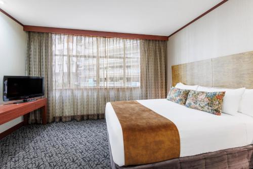 a hotel room with a bed and a flat screen tv at Adina Citylife Wellington in Wellington