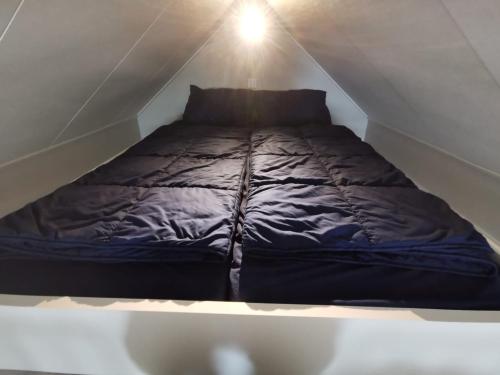 a bed sitting in the middle of a attic at Tiny Haus Auszeit am See in Lathum