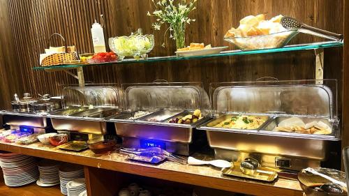 a buffet with several trays of food on a table at Rosa May Hotel in Ho Chi Minh City