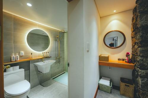 uma casa de banho com um WC, um lavatório e um espelho. em Dazayo WolryeongBadang House - Ocean View & Pet Frindely em Jeju