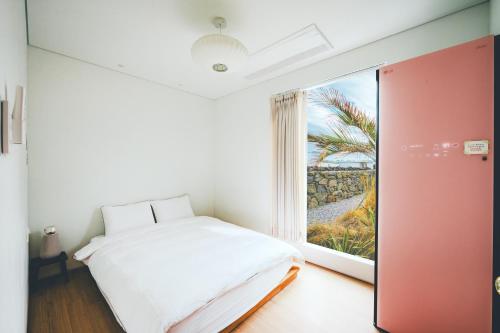 um quarto com uma cama e uma grande janela em Dazayo WolryeongBadang House - Ocean View & Pet Frindely em Jeju