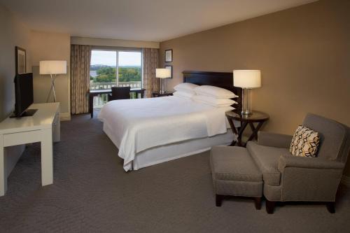 a hotel room with a bed and a chair and a television at Sheraton Louisville Riverside Hotel in Jeffersonville