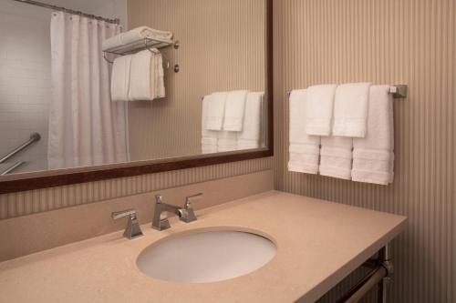 a bathroom with a sink and a mirror and towels at Sheraton Louisville Riverside Hotel in Jeffersonville