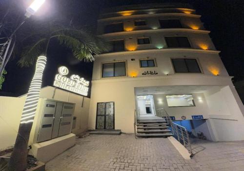 a building with a palm tree in front of it at Gold Pine Hotel Lahore in Lahore