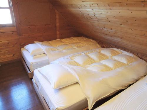 two beds in a room with a wooden wall at Kokoro no sato in Kamishihoro
