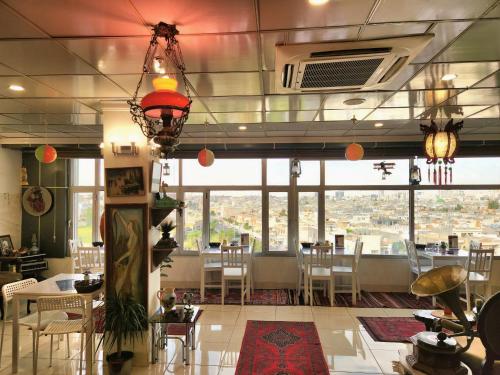 een restaurant met tafels en stoelen en een groot raam bij Vote Hotel in Erbil