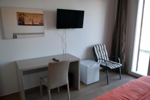 1 dormitorio con escritorio, TV y silla en Granatelli Holiday Home, en Altavilla Milicia