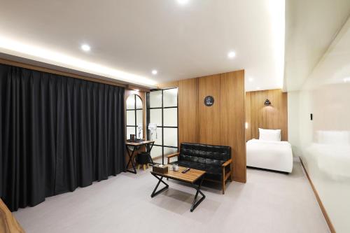 um quarto de hotel com uma cama, um sofá e uma mesa em Jeonju Urban Hotel em Jeonju