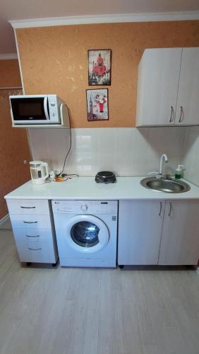 Il comprend une cuisine équipée d'un lave-linge et d'un évier. dans l'établissement 1 комнатная квартира в Щучинске, à Chtchoutchinsk