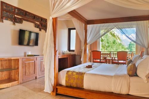 a bedroom with a canopy bed and a balcony at Green Field Resort Ubud in Ubud