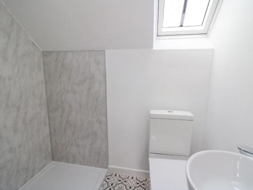 a bathroom with a toilet and a sink and a window at The Old Stable in Tondu