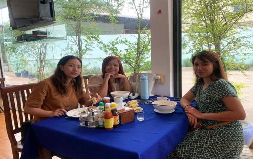 three women sitting at a table with a blue table cloth at Blossoming Romduol Boutique in Siem Reap