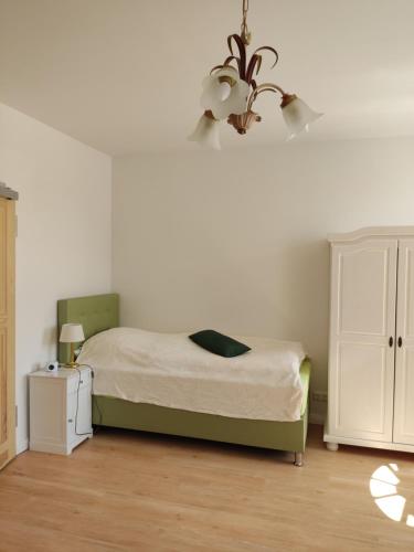 1 dormitorio con cama y lámpara de araña en Inspektorenhaus Dobbin Ferienpension en Linstow