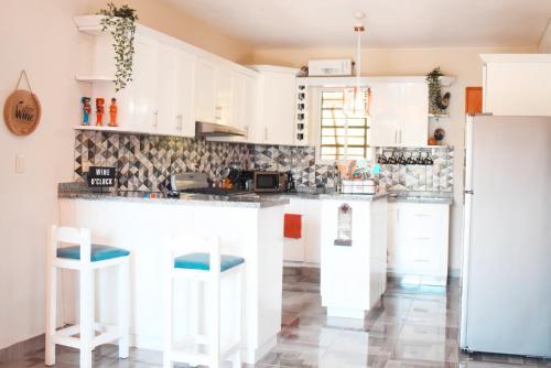 a kitchen with white cabinets and a counter with stools at Villa Rodriguez Jarabacoa in Jarabacoa