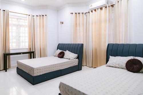a bedroom with two beds and a window with curtains at Villa Seputeh Kuala Terengganu in Kuala Terengganu