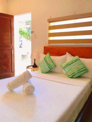 a bedroom with a bed with green and white pillows at Victoria's Inn by Martha Vacation Homes in Boracay
