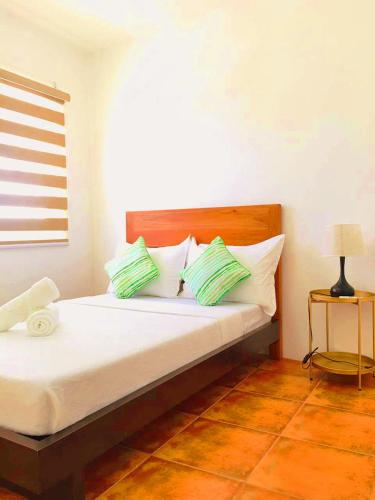 a bedroom with a bed with green and white pillows at Victoria's Inn by Martha Vacation Homes in Boracay