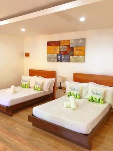 two beds in a hotel room with white sheets at Victoria's Inn by Martha Vacation Homes in Boracay