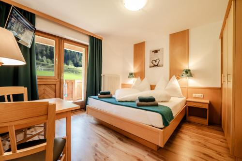 Oberlehenhof في كابرون: غرفة نوم بسرير ومكتب ونافذة