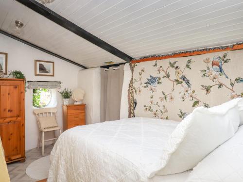 ein Schlafzimmer mit einem weißen Bett und einer Blumenwand in der Unterkunft Sunset Cottage in Barnstaple