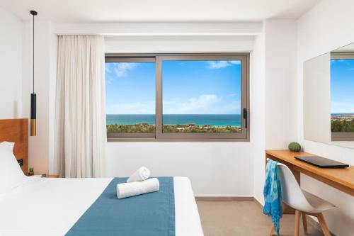 a bedroom with a bed and a desk and a window at Diamond Star Hotel in Falasarna
