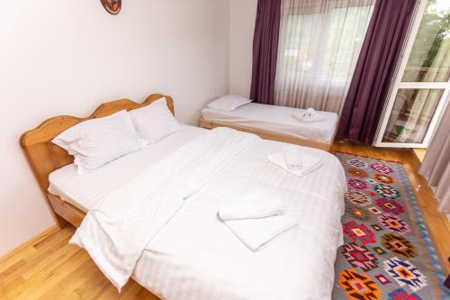 a bedroom with a bed with white sheets and a window at CASA RUMELIA in Păltineni