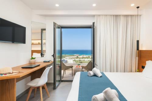 a hotel room with a bed and a desk and a view of the ocean at Diamond Star Hotel in Falasarna