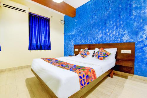 a bedroom with a bed with a blue wall at FabHotel Ashirwad in Pilerne