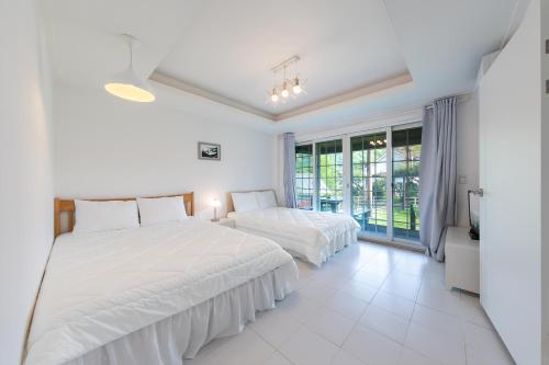 two beds in a white room with a window at Walking Sky Pension in Gapyeong