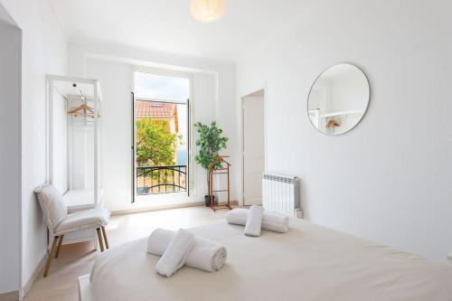 une chambre blanche avec un grand lit et un miroir dans l'établissement Les lucioles, à Beausoleil