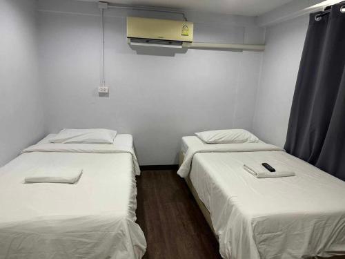 two beds in a room with white walls at GO INN Chiang Mai University - CMU โกอินน์ มหาวิทยาลัยเชียงใหม่ in Chiang Mai
