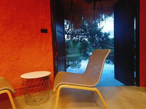 dwa krzesła i stół przed oknem w obiekcie Khao Yai Lake Hill Resort เขาใหญ่เลค ฮิลล์ รีสอร์ท w mieście Khanong Phra