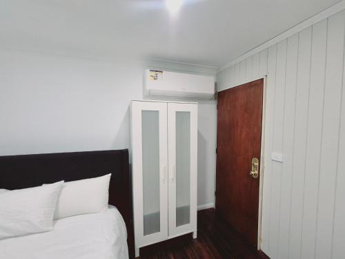 a bedroom with a white bed and a wooden door at Kaban Power 39 in Bidwill