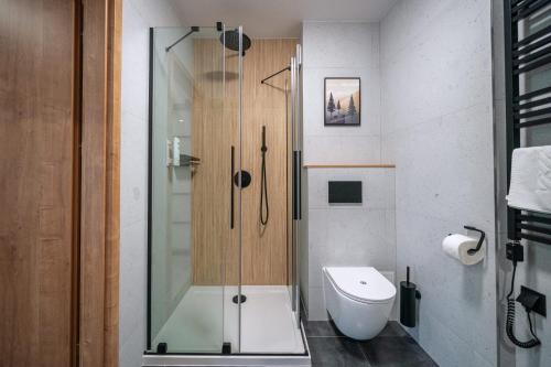 a bathroom with a glass shower and a toilet at Kompleks Antałówka Termy & Med in Zakopane