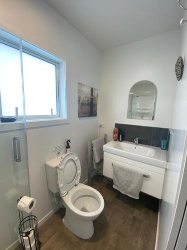 a white bathroom with a toilet and a sink at Aratahi Cottages in Carterton