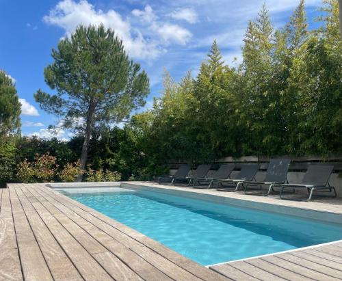 - une piscine avec des chaises sur une terrasse en bois dans l'établissement Villa (Loft) à Villetelle, 20 mn des plages, à Villetelle