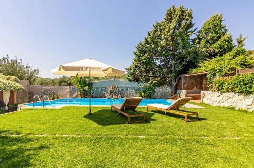 a yard with two chairs and an umbrella and a pool at DM Elegant and Charming Villa in Foinikiá