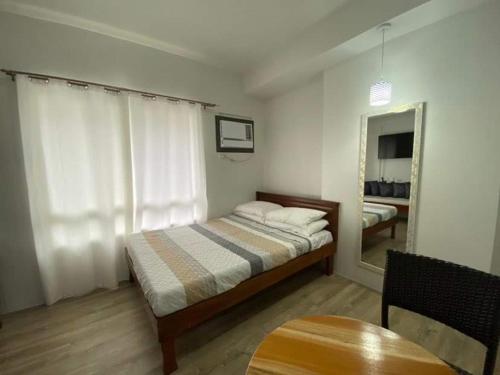 a bedroom with a bed and a table and a mirror at Isabela 1 Mesavirre Residences in Bacolod