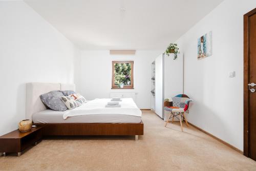 - une chambre blanche avec un lit et une chaise dans l'établissement Apartmány Jako doma, à Plzeň