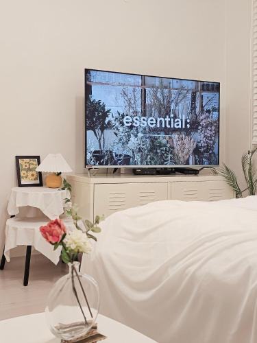 a bedroom with a tv and a bed and a vase with flowers at Seoul 리베하우스 3room KSPO-DOM Family trip in Seoul