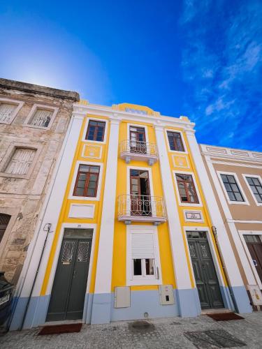 a yellow and white building with a balcony at Casinha Amarela in Figueira da Foz
