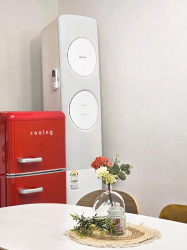 a vase of flowers on a table with a refrigerator at Seoul 리베하우스 3room KSPO-DOM Family trip in Seoul