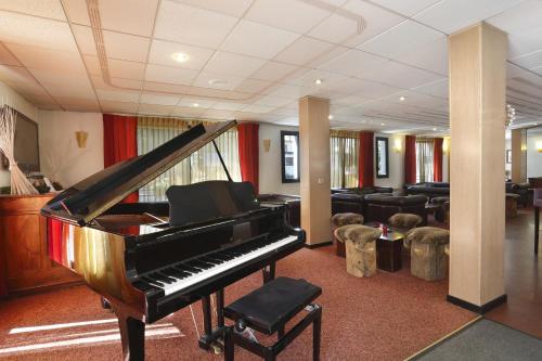 a piano in a room with a living room at Hotel Amélie in Brides-les-Bains